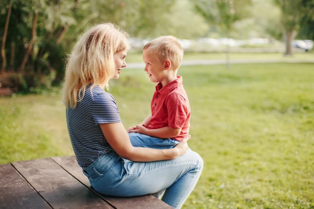 Moeder met zoontje op schoot. Zij stemt zich op hem af. Hij leert van haar  zijn emoties te herkennen en verwoorden evenals de onderliggende behoeften.